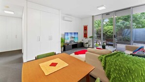 Ein modernes Wohnzimmer mit Essbereich, großen Fenstern und Blick auf Grünfläche.