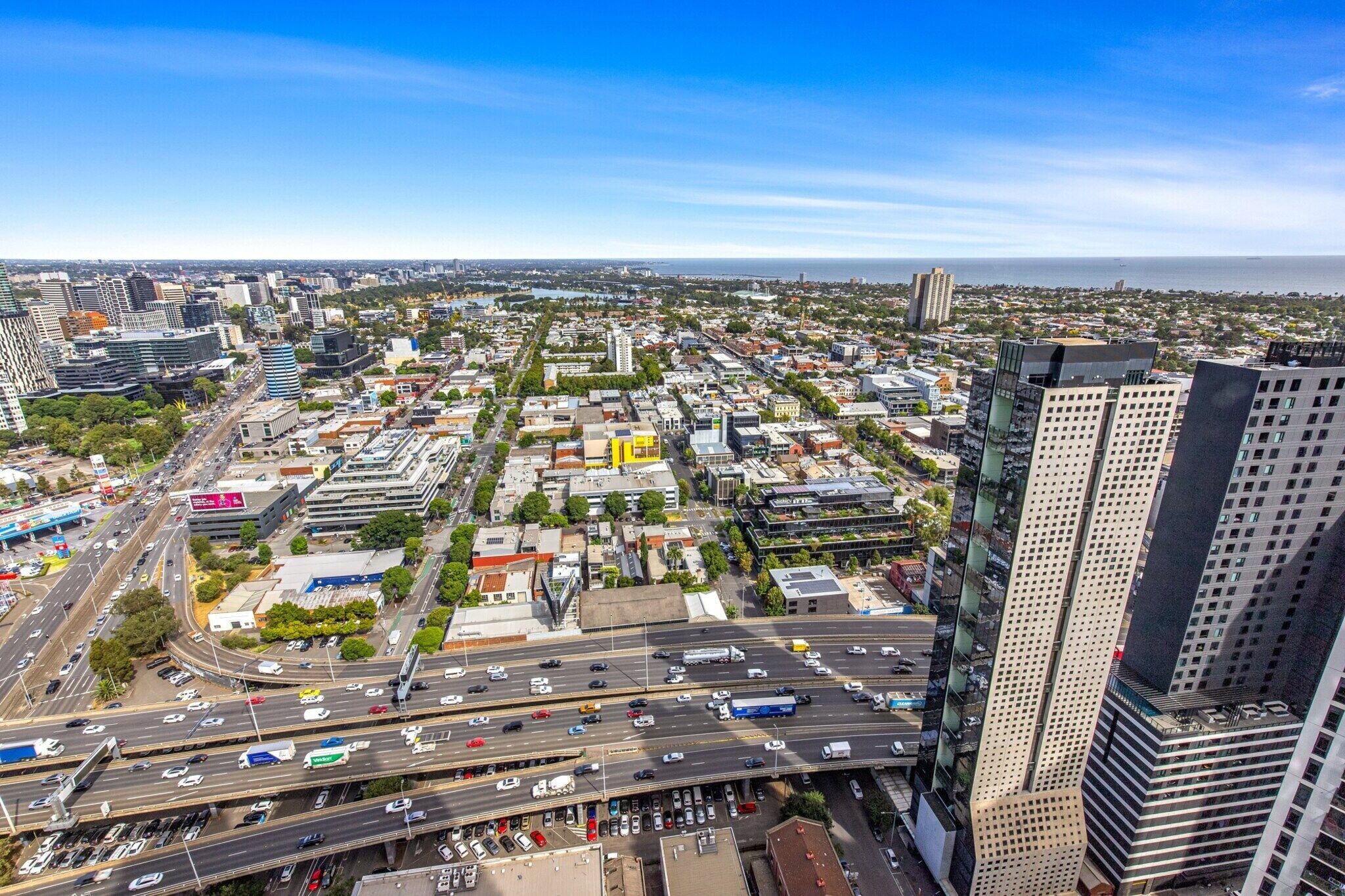 A cityscape with multiple high-rise buildings, a busy highway, and a clear sky.