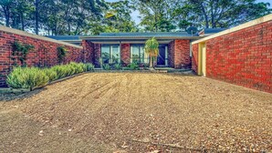 A modern house with a brick exterior, a gravel driveway, and a small garden with various plants. - Spacious 2-Bed Townhouse with BBQ (Surf Beach)