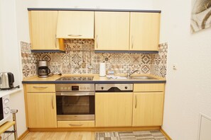 Cuina compacta amb armaris de fusta, forn integrat, cafetera i rentaplat.
