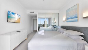 Una camera d'albergo moderna con un letto grande, una cassettiera bianca e vista sulla città attraverso la porta vetrata.