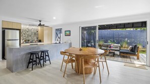 Une cuisine moderne dotée d’un îlot central, de tabourets de bar et d’un coin repas avec une table ronde et des chaises.