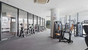 Une salle de sport moderne, dotée de divers appareils d’entraînement, de grandes fenêtres et d’un aménagement propre et spacieux.