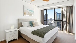 Een moderne hotelkamer met een groot bed, een plafondventilator, een nachtkastje, een raam met uitzicht op de stad en een lijst met kunstwerk aan de muur.