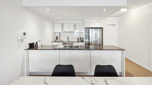 Een moderne keuken met witte kastjes, een roestvrijstalen koelkast en een marmeren aanrecht.