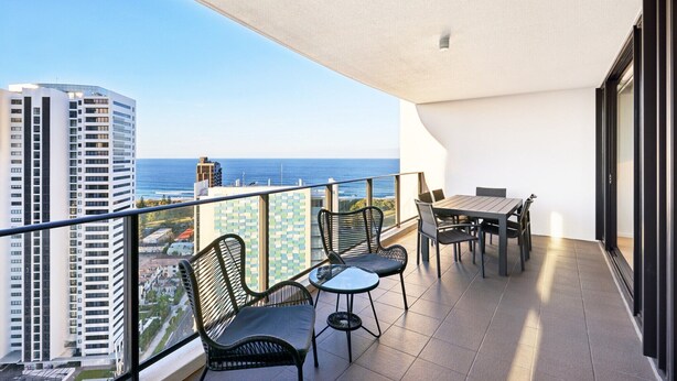 Een balkon met een tafel en stoelen, met uitzicht op een stadsbeeld en de zee.