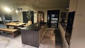 Een moderne keuken met een centraal eiland, houten banken en een inbouwkast.