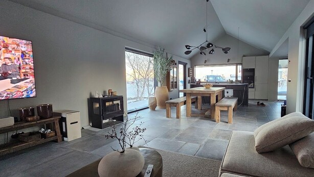 Een moderne woonkamer met een grote televisie, een bank, een eethoek en een keuken.