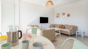 A modern living room with a sofa, a coffee table, and a TV. There is a dining table with cups and a kettle. - Terrace apartment Puget-sur-Argens (Puget-sur-Argens)