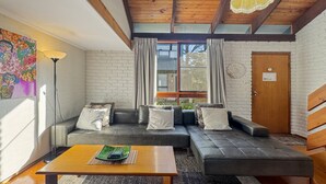 Un salon moderne avec un canapé, une table basse et une grande fenêtre agrémentée de rideaux.