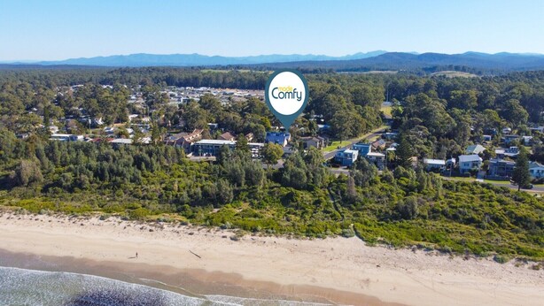 Vue aérienne d’une zone côtière avec une plage, des immeubles résidentiels et un logo portant la mention « mode Confort ».