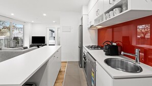Eine moderne Küche mit weißen Schränken, einer Edelstahl-Spüle und einer roten Rückwand.