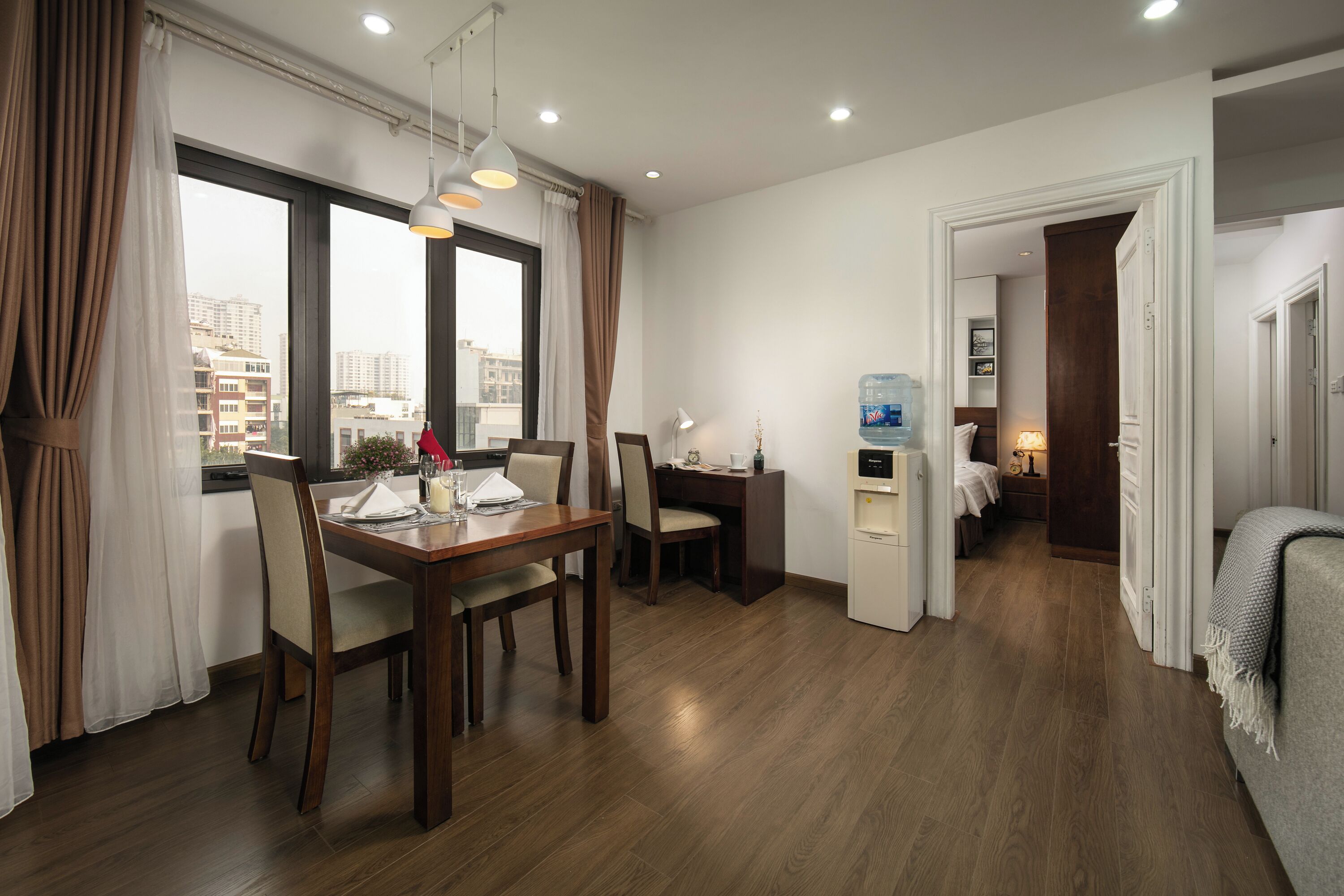 Una habitación de hotel moderna con comedor, kitchenette y vistas a la ciudad.