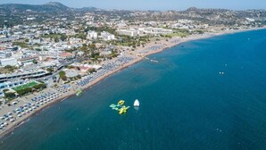Vista aérea de una ciudad costera con playa, edificios y agua azul cristalina.