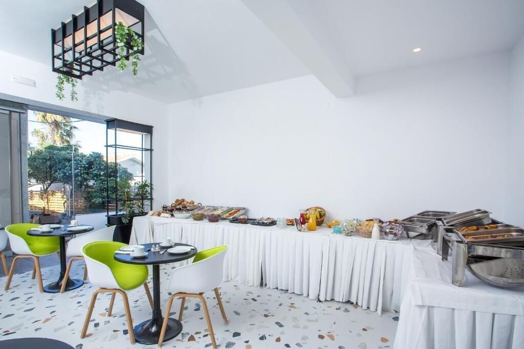 Un espace repas moderne avec un buffet, des chaises vertes et blanches, et une plante suspendue.