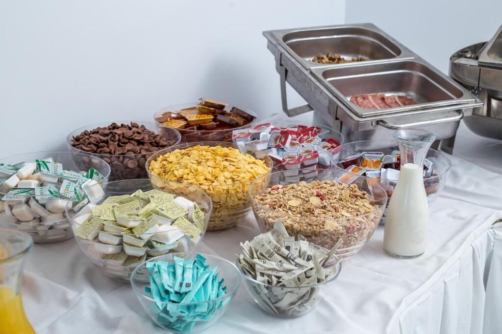Una mesa de buffet con diversos alimentos, como cereales, bocadillos y productos lácteos.