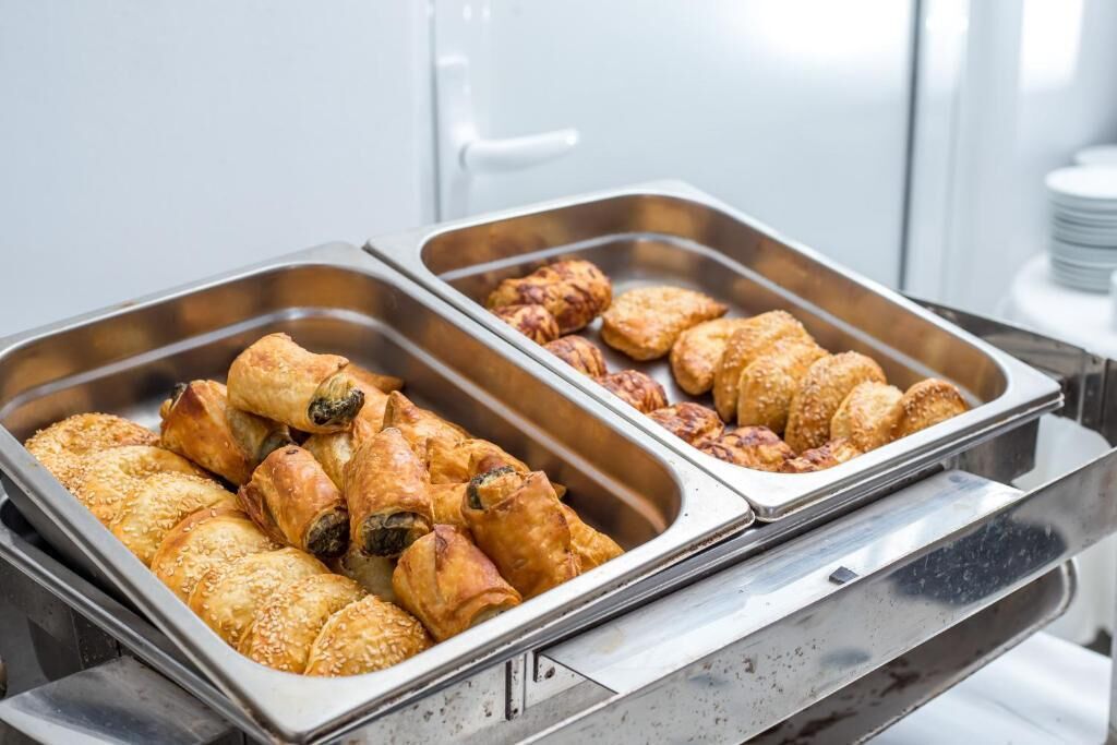 A buffet with various baked goods, including pastries and bread rolls.