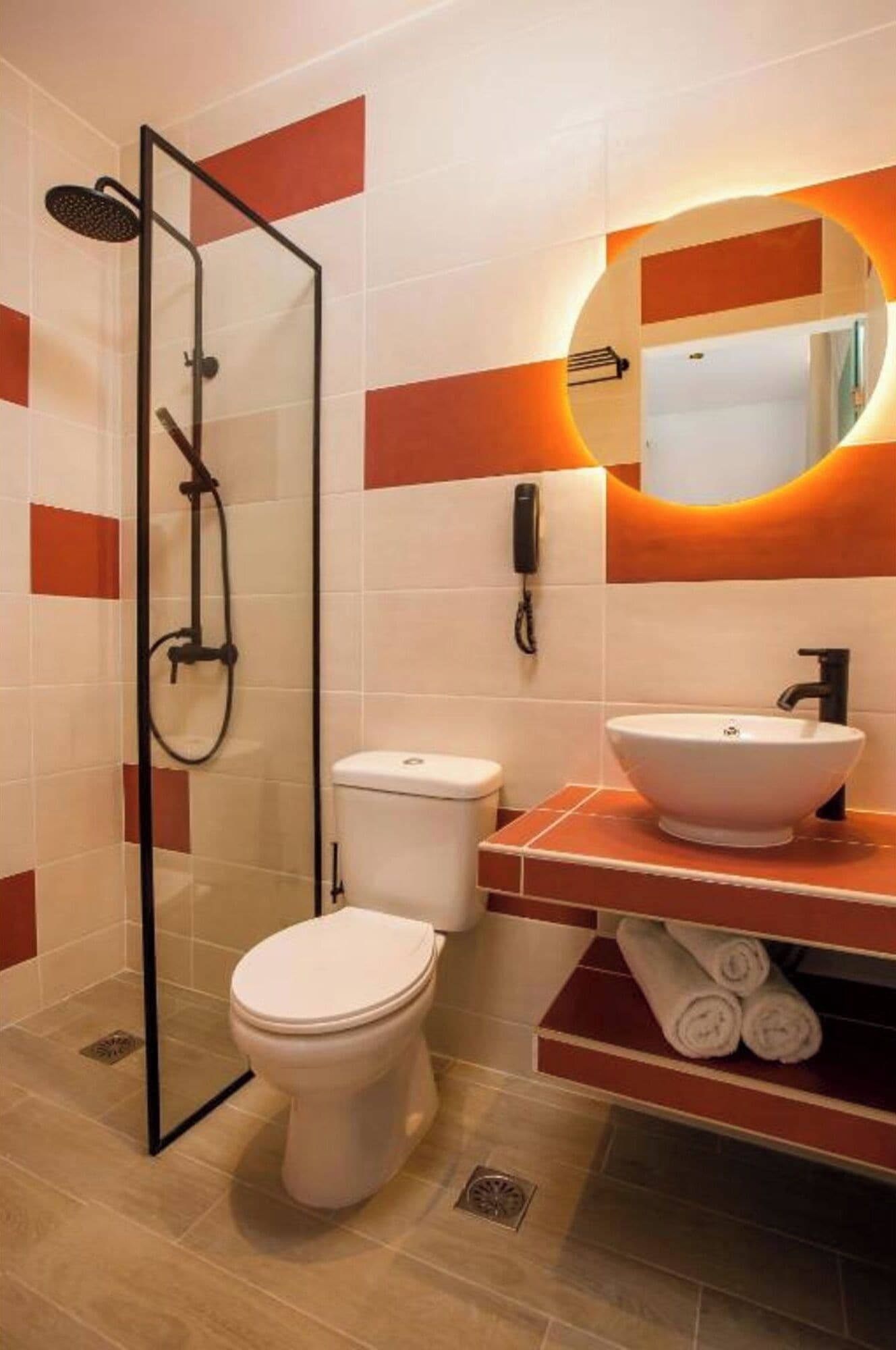 A modern bathroom with a glass-enclosed shower, a white toilet, a sink with a mirror, and a towel rack.