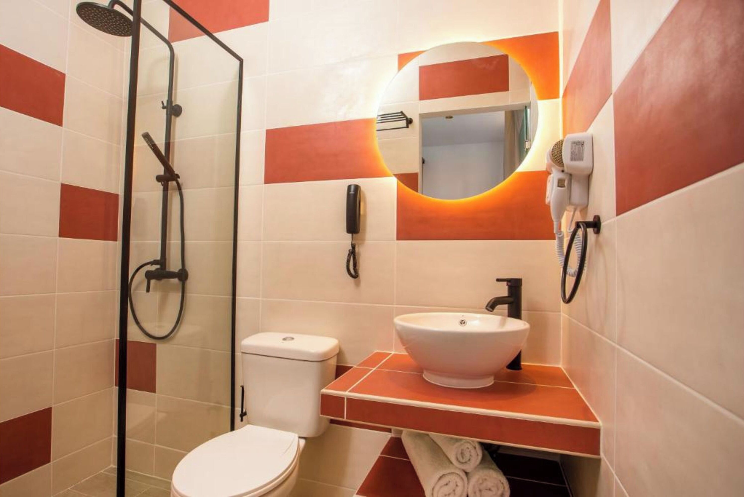 A bathroom with a glass-enclosed shower, a white toilet, and a sink with a mirror above it.