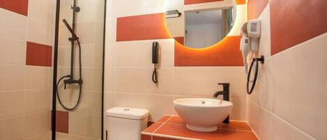 A bathroom with a glass-enclosed shower, a white toilet, and a sink with a mirror above it.