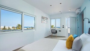 Una habitación de hotel moderna con una cama grande, una silla y vistas al mar.