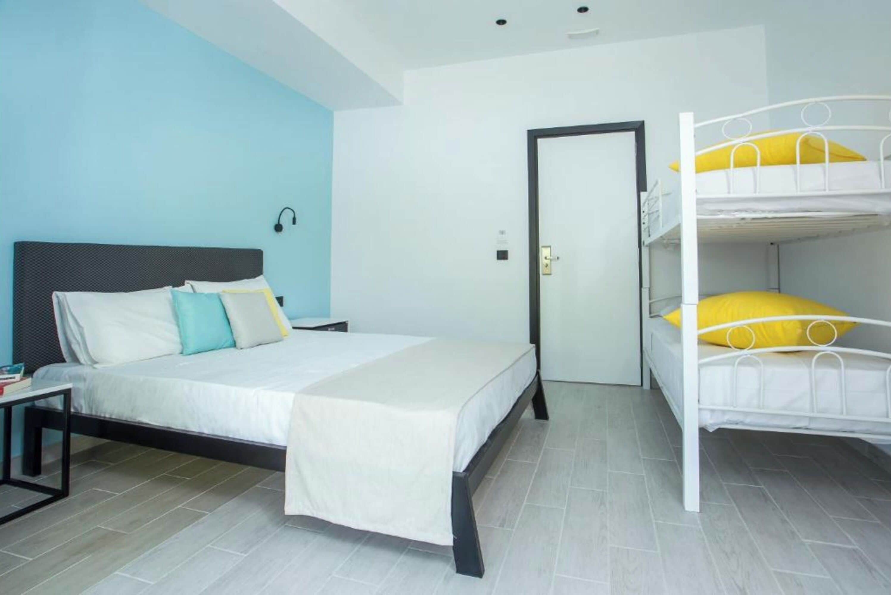Un dormitorio con una cama individual, una litera, una mesita de noche y un velador.