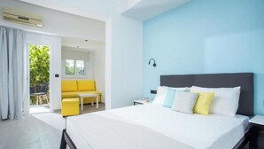 Una habitación de hotel moderna con una cama grande, un sofá amarillo y una mesita pequeña.