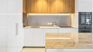 Una cocina moderna con armarios blancos, una sección superior de madera, un lavamanos de acero inoxidable y un horno empotrado.