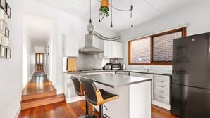 Cozinha moderna com ilha central, eletrodomésticos de aço inoxidável e piso de madeira.