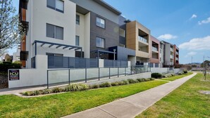 Un immeuble d’appartements moderne, doté d’un toit plat, de grandes fenêtres et d’une entrée sécurisée par un portail.