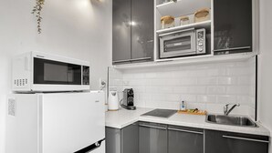 Une cuisine moderne équipée d’un réfrigérateur blanc, d’un four à micro-ondes, d’un grille-pain et d’un évier.