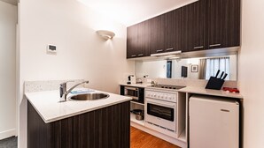 A compact kitchen with a built-in oven, a refrigerator, and a sink. - Chic 1-Bed in East Melbourne with Gym & Pool (East Melbourne)
