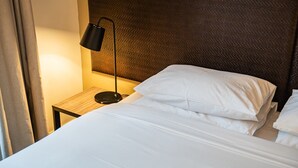 A neatly made bed with white linens and pillows, a black floor lamp, and a textured headboard. - Chic 1-Bed in East Melbourne with Gym & Pool (East Melbourne)