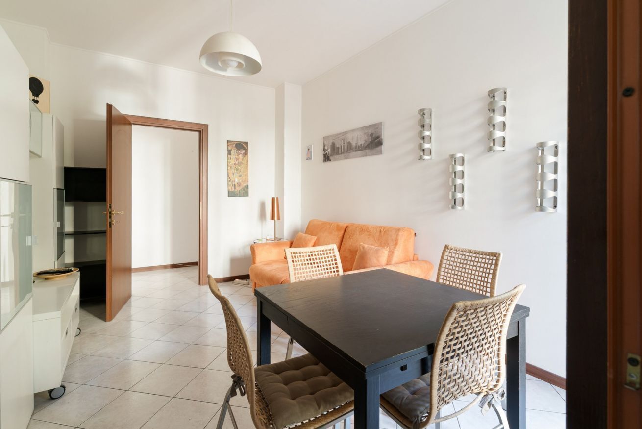 A dining area with a table and chairs, a sofa, and a kitchen area with cabinets and a refrigerator.