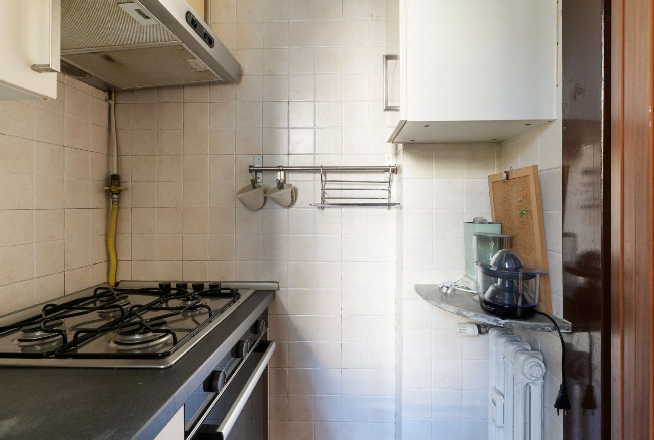 Une cuisine équipée d’une cuisinière à gaz, d’un four encastré, d’un porte-serviettes mural et d’un petit réfrigérateur.