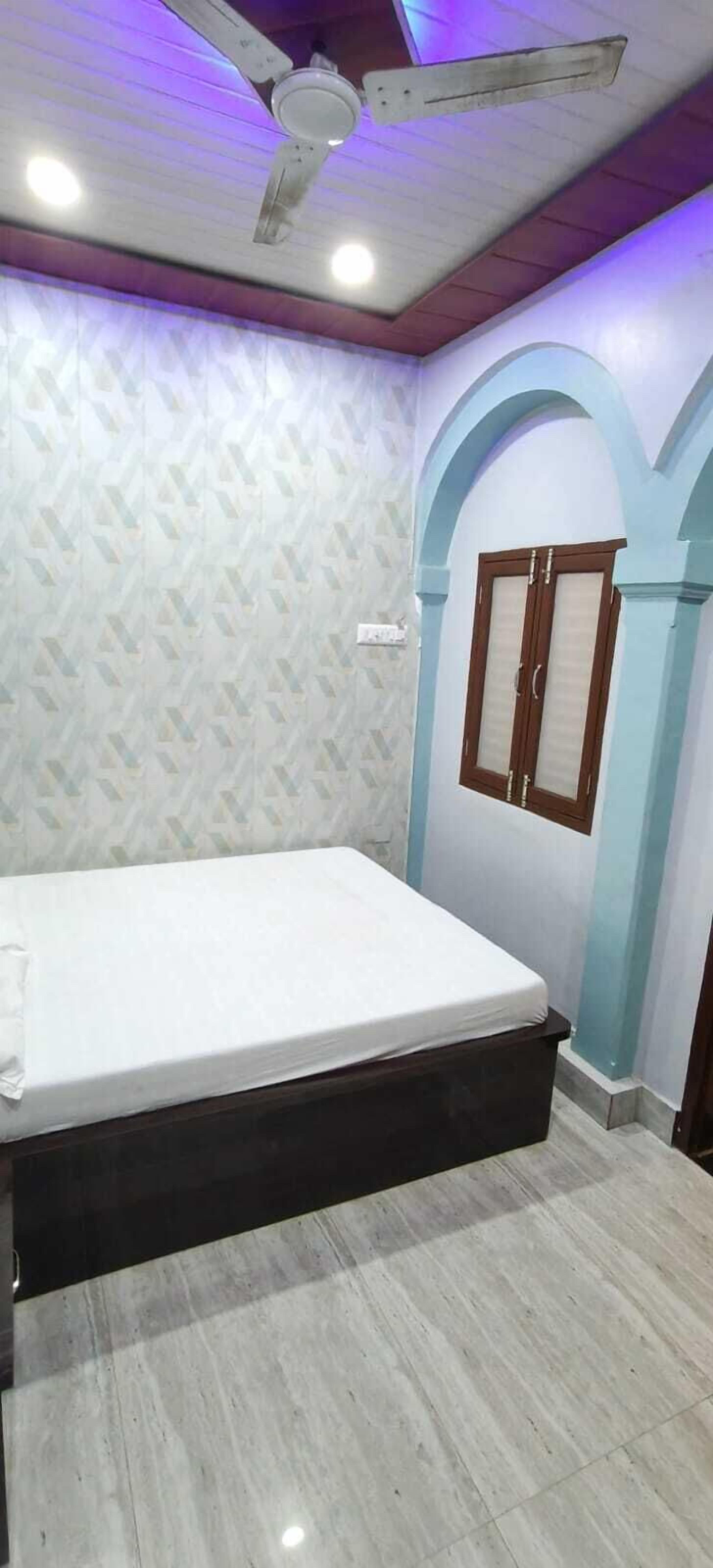 A bedroom with a bed, a ceiling fan, and a window with curtains.