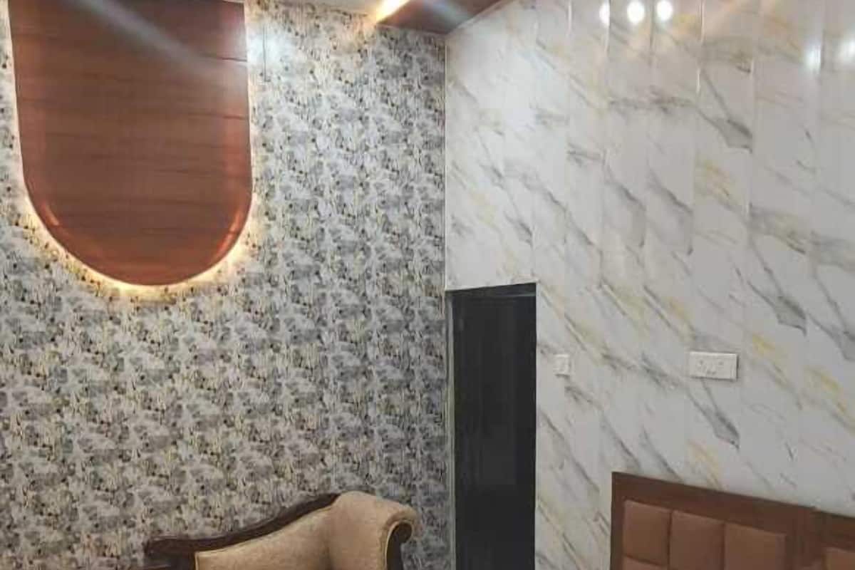 A bedroom with a bed, a sofa, a TV, and a ceiling fan.
