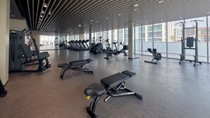Ein modernes Fitnessstudio mit unterschiedlichen Trainingsgeräten, großen Fenstern und einem außergewöhnlichen Deckenstil.