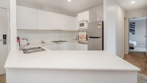 Eine moderne Küche mit weißen Schränken, einer Kochinsel, einem Einbauofen und einem Kühlschrank.