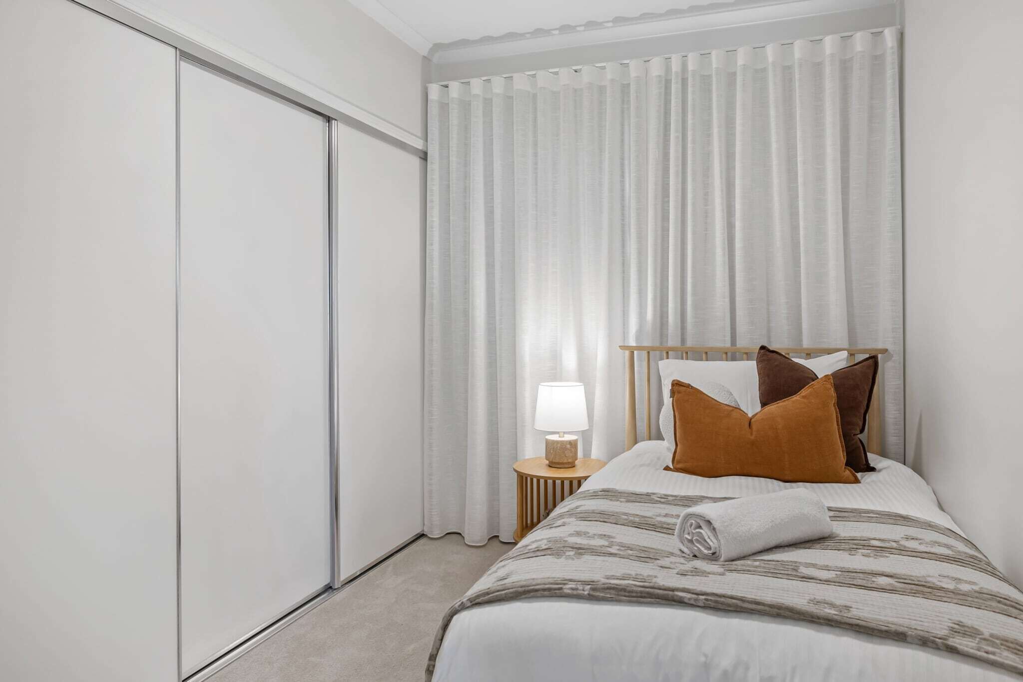 A hotel room with a bed, a nightstand with a lamp, and a sliding door.