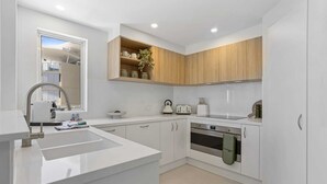 A modern kitchen with white cabinetry, a stainless steel sink, and a built-in oven.