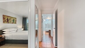 Quarto de hotel com cama, quadro e vista para uma varanda através de uma porta aberta.
