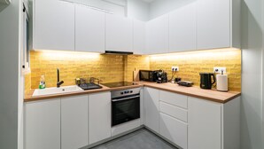 Eine kompakte Küche mit weißen Schränken, einer Holzarbeitsplatte, einem eingebauten Backofen und einer Mikrowelle.