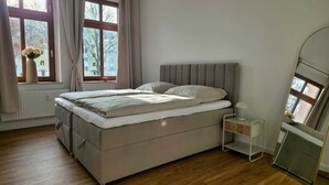 Une chambre à coucher avec un lit, une table de chevet et une fenêtre avec des rideaux.