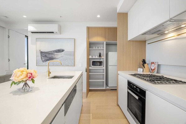 Une cuisine moderne avec des meubles blancs, un four à micro-ondes encastré et une cuisinière à gaz.
