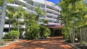 A multi-story hotel with balconies, palm trees, and a brick pathway leading to the entrance. - Resort-Style Stay with Balcony & Garage Parking (Torquay)