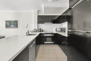 Une cuisine moderne dotée d’un grand îlot central, d’appareils électroménagers en acier inoxydable et d’un four à micro-ondes.