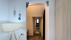 Ein Flur mit einer Lampe, einer Wandleuchte und einer Tür zu einem anderen Raum.