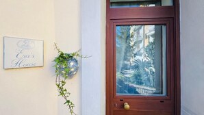 Eine Holztür mit Glasschiebeelement, ein Schild mit der Aufschrift 'Eve's House' und eine hängende Pflanze mit Ranken.