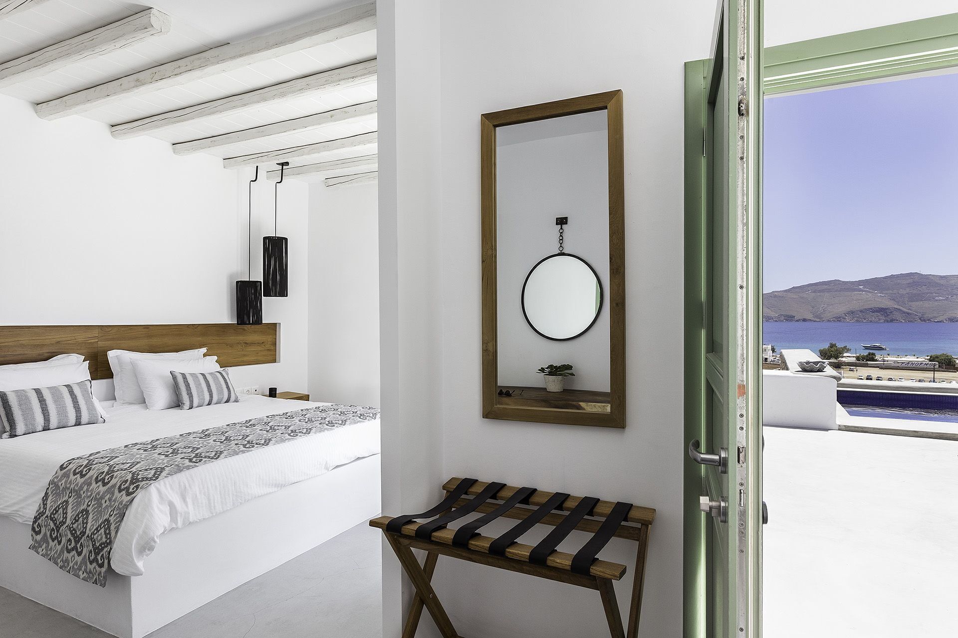 Une chambre à coucher moderne avec un grand lit, une table de chevet, un miroir et une vue sur la mer.